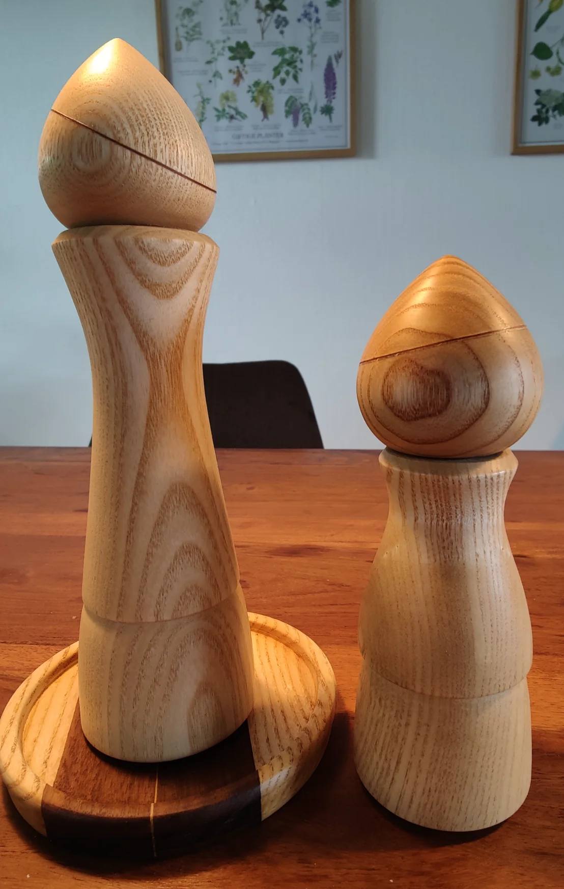 a big and a small pepper grinder in a light wood